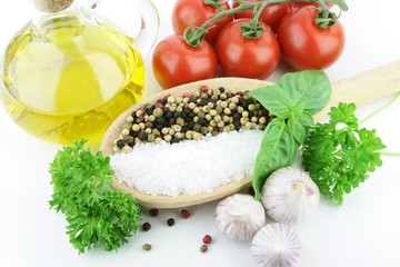 Salt and Pepper on a big wooden spoon, with some herbs around it. On a white background. Top view.