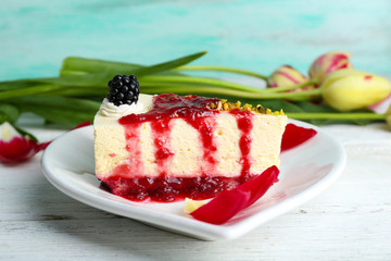 Tasty piece of cheesecake with berry sauce on plate on table close up