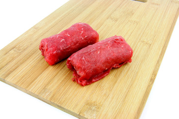 Dutch meat roll called "Blinde vink" made of veal ground beef with a thin cutlet of veal on the outside, on a cutting board.