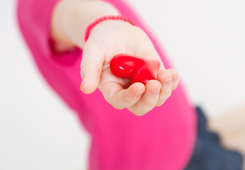 Unrecognizable little girl holding a red heart