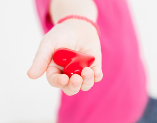 Unrecognizable little girl holding a red heart