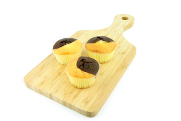 Plain and chocolate muffins on a wooden board.