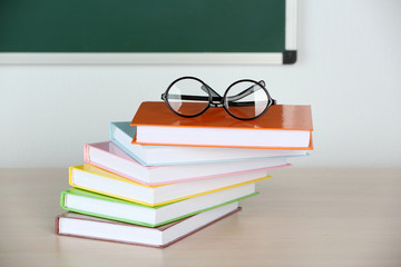 Heap of books and glasses on table in class
