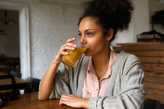 Young mixed race woman drinking orange juice