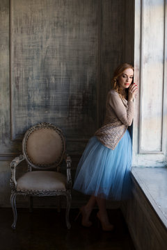 Elegant woman is standing near the window in luxury interior room