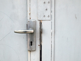 Aluminium door knob on the white door