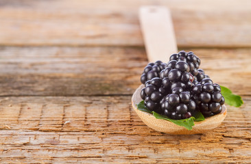 blackberries in spoon on wooden background