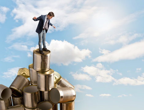 Young businessman balancing on a tower of cans