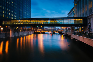 Buildings and pedestrian bridge over the Milwaukee River at nigh
