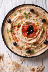 Hummus with olives, tomatoes and herbs vertical top view
