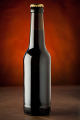 Bottle of beer on a stone table over brown background