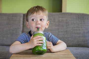 Fototapeta premium Little boy drinking a green smoothie