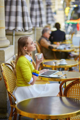 Young romantic Parisian girl drinking coffee