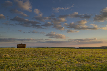 tank in middle of field at sunset