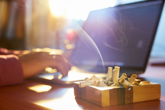 Man Using Laptop And Smoking Cigarette In The Morning