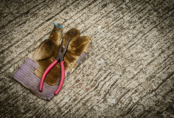 Still life with old locking plier and old glove on grunge background