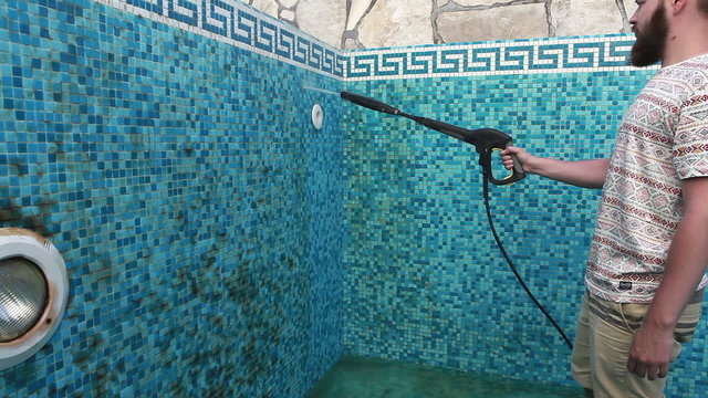 A man is cleaning the pool wall