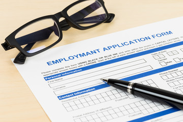 Employment application form with pen and glasses; form is mock-u