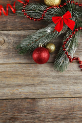 Fototapeta na wymiar Branch of Christmas tree with balls on grey wooden background