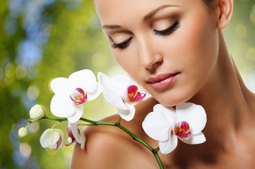 Face of  beautiful woman with a white orchid flower