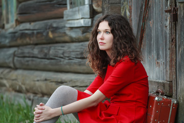 Young woman sitting on threshold of old log cabin