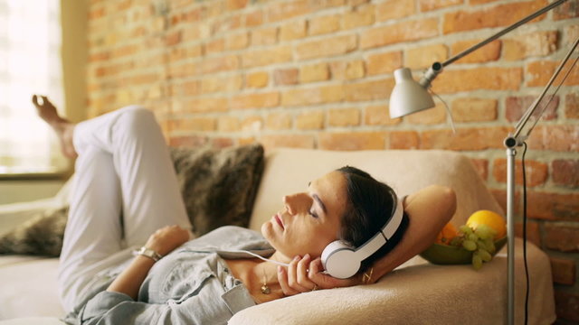 Woman chilling on the sofa and listening music

