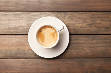 Cup of coffee on wooden table, top view