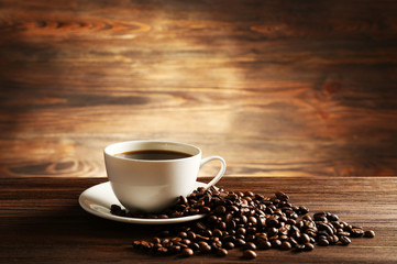 Cup of coffee with grains on wooden background