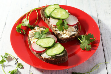 Delicious sandwiches with vegetables and greens on plate on table close up