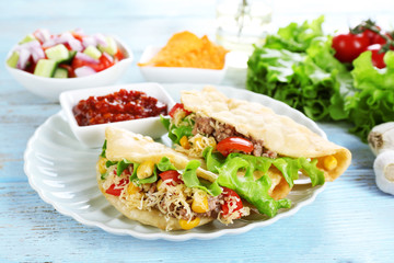 Tasty taco with tomato dip on plate and vegetables on table close up