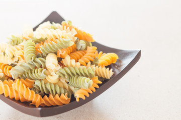 Raw fusilli pasta on wooden tray