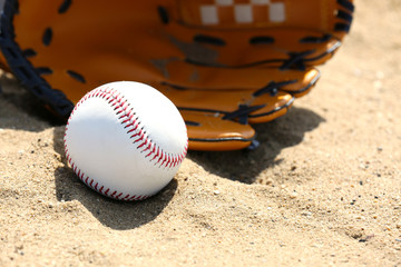 Baseball ball and glove on sand