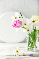 Obraz na płótnie Canvas Spring bouquet in glass mug on color wooden background