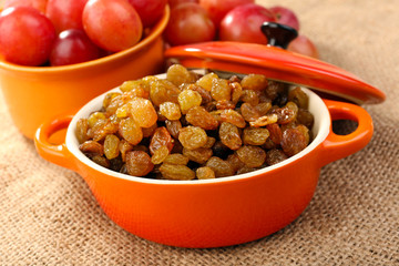 Raisins in bowl with grapes on table close up