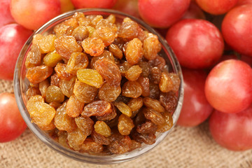 Raisins in bowl with grapes on table close up