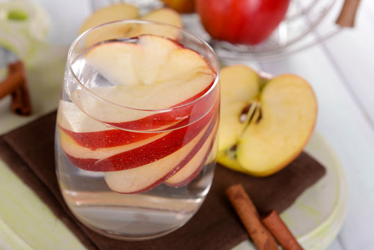 Glass of apple cider with fruits and cinnamon on table close up