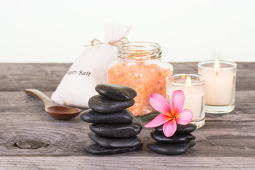 Spa with bath salt, black stones and candles on wooden table close up