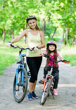 mom and daughter ride bikes in the park