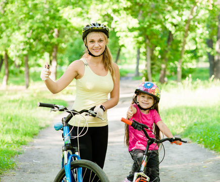 happy mother and daughter having fun, riding a bicycle and showi