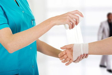 Woman doctor bandaging female hand.