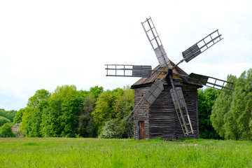 Plakat Old wooden windmills on green field, on blue sky background