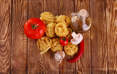 pasta on the wooden background with tomato, pepper, olive oil, mushrooms and lettuce