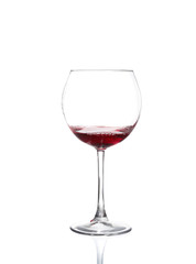 Red wine pouring from bottle into big glass on white background