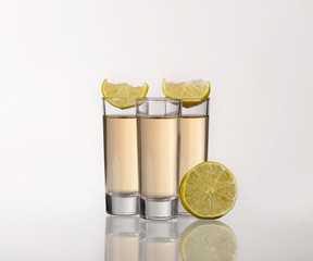 Three gold tequila shots with lime  on white background