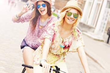 Two girl friends riding tandem bicycle