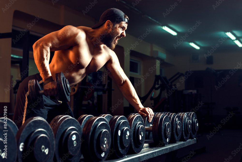 Wall mural muscular male bodybuilder working out in gym