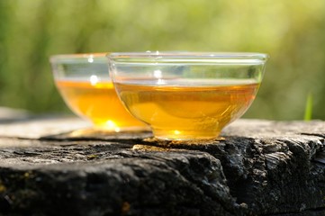 Two transparent cups of black tea on old wooden board in bright