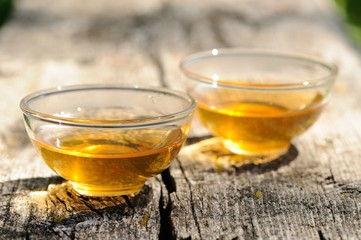 Two transparent cups of black tea on old wooden board in bright