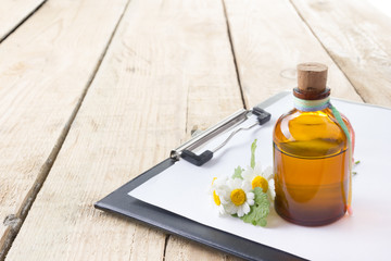 Fresh herb, bottle and medical clipboard on wooden table. Alternative medicine concept.