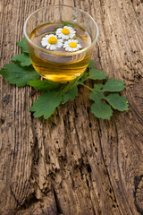 Herbal tea with chamomile on old wooden table. 